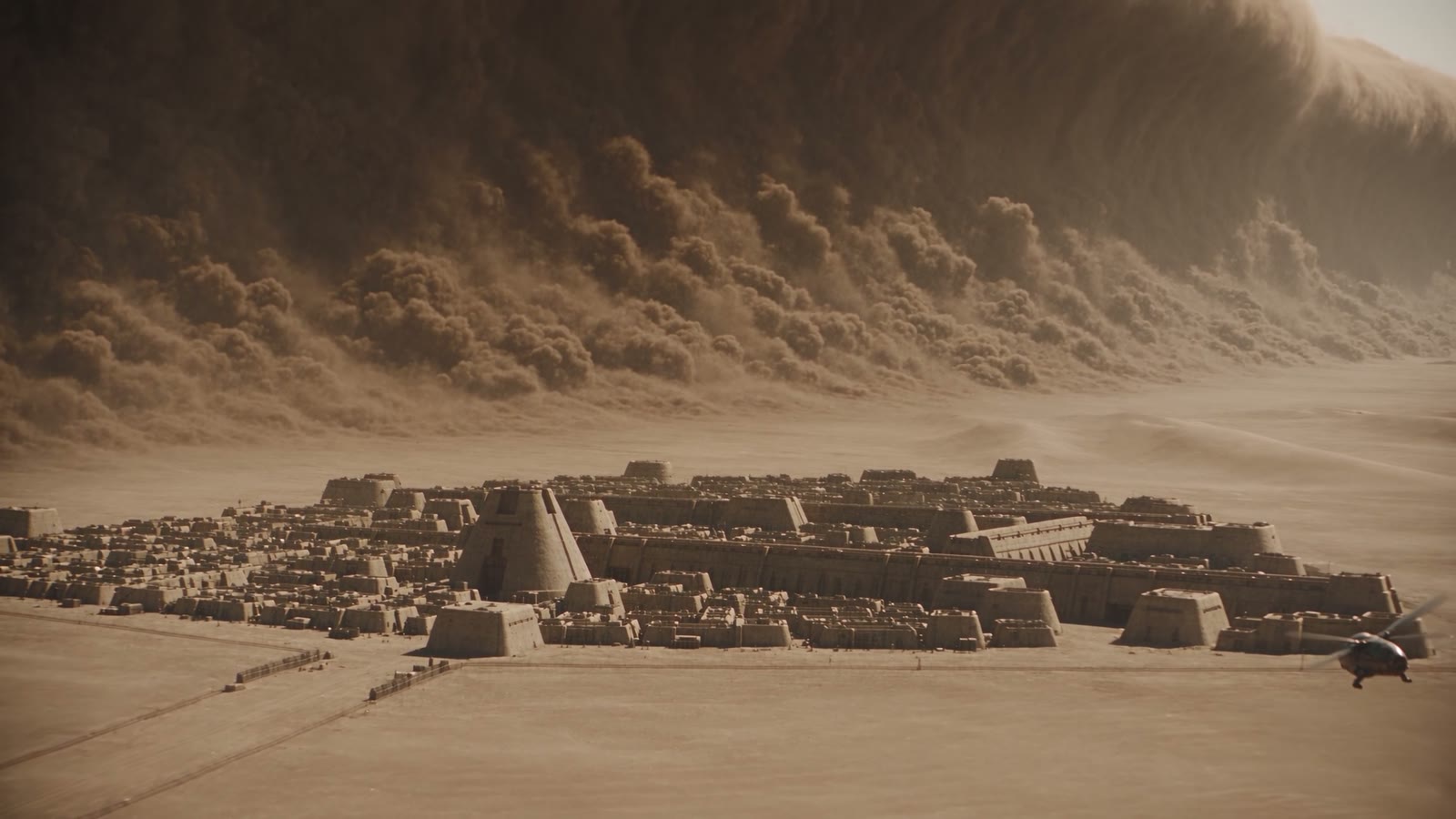 The city of Arrakeen beneath an approaching wall of sandstorm